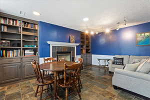Dining area with a tile fireplace, built in features, a textured ceiling, and dark stone finish floors