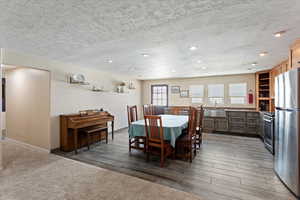 Dining space with recessed lighting, light wood finished floors, a textured ceiling, and light colored carpet