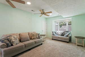 Carpeted living area featuring a ceiling fan, recessed lighting, and a textured ceiling