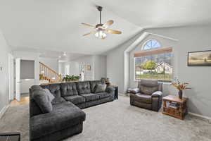 Living room featuring carpet, vaulted ceiling, ceiling fan.