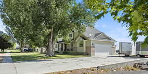 View of front of property with driveway, an attached garage, roof with shingles, brick siding, and a front yard