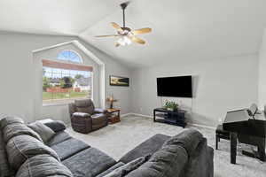 Carpeted living room with vaulted ceilings and a ceiling fan