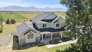 View of front of house featuring a mountain view, a front lawn, a rural view, and roof with shingles