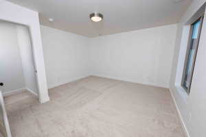 Unfurnished bedroom with baseboards and light colored carpet