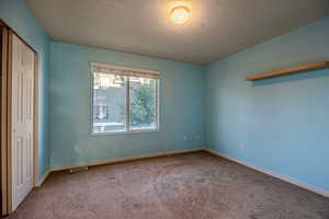 Unfurnished bedroom with a textured ceiling, carpet floors, and a closet