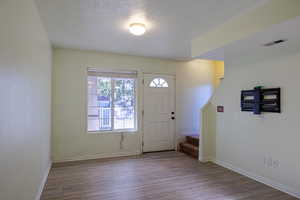 Foyer with wood finished floors, a textured ceiling, and stairway
