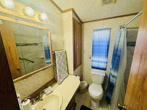 Full bath with wallpapered walls, ornamental molding, shower / tub combo with curtain, and vanity