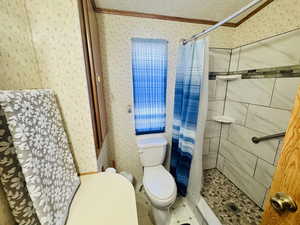 Bathroom featuring a stall shower, wallpapered walls, ornamental molding, a textured ceiling, and tile patterned flooring