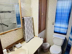 Bathroom with wallpapered walls, vanity, tiled shower / bath combo, and tile patterned floors