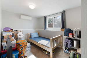 Bedroom with carpet floors and a wall mounted air conditioner