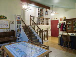 Dining room featuring ceiling fan, light tile patterned floors, a chandelier, and stairs