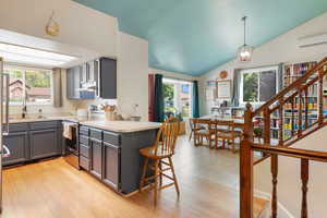 Kitchen with gray cabinets, stainless steel range with electric cooktop, vaulted ceiling, plenty of natural light, and light countertops