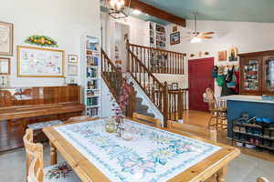 Dining space featuring ceiling fan, tile patterned flooring, stairway, and a chandelier