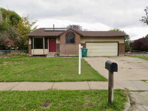 View of front facade featuring roof mounted solar panels, driveway, brick siding, a garage, and a shingled roof