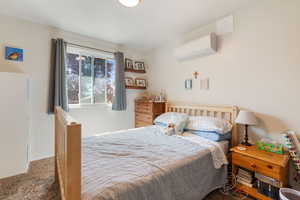 Carpeted bedroom featuring an AC wall unit