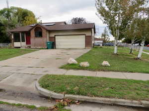 View of front facade with brick siding, concrete driveway, solar panels, and a garage
