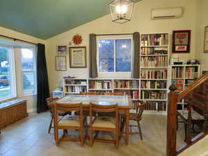 Sitting room featuring healthy amount of natural light, a wall mounted AC, vaulted ceiling, and tile patterned flooring