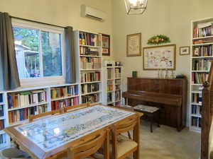Sitting room featuring a wall unit AC, bookshelves, and a chandelier