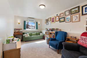 Living area with carpet flooring and a wall unit AC