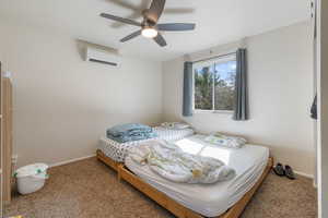 Bedroom with carpet floors, an AC wall unit, and a ceiling fan