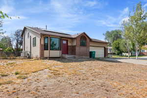 Single story home featuring driveway, roof mounted solar panels, an attached garage, and entry steps