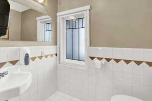 Bathroom with tile walls, tile patterned floors, and a wainscoted wall