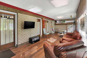 Living area featuring brick wall, a textured ceiling, and wood finished floors
