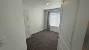 Empty room featuring dark colored carpet and a textured ceiling