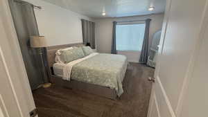 Bedroom with dark carpet and a textured ceiling