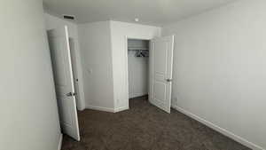 Unfurnished bedroom with dark colored carpet and a closet