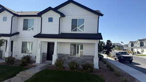 Craftsman-style house with stone siding, a porch, a residential view, and board and batten siding