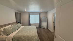 Bedroom with dark carpet and a textured ceiling