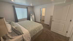 Bedroom with dark carpet, recessed lighting, ensuite bath, and a textured ceiling