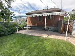 Back of house with brick siding, covered patio,  gate, and long metal entertaining table