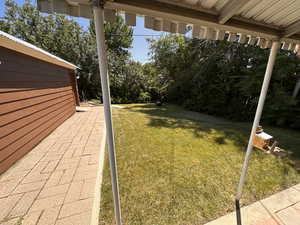 View of paver patio, side of garage and birdhouse