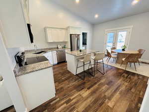 Kitchen with light stone counters, a kitchen island, appliances with stainless steel finishes, a kitchen bar, and recessed lighting