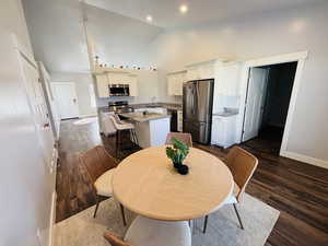 Dining room with dark wood-style floors and high vaulted ceiling