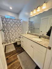 Bathroom with shower / bath combo with shower curtain, vanity, dark wood finished floors, and recessed lighting