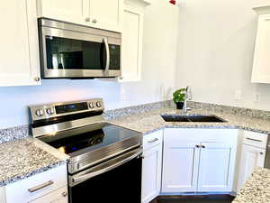 Kitchen featuring stainless steel appliances, white cabinets