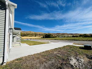 View of grassy yard featuring a mountain view and a patio
