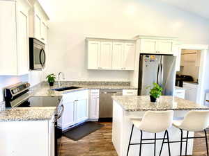 Kitchen with appliances with stainless steel finishes, wood finished floors, an island bar, granite countertops. All appliances stay.