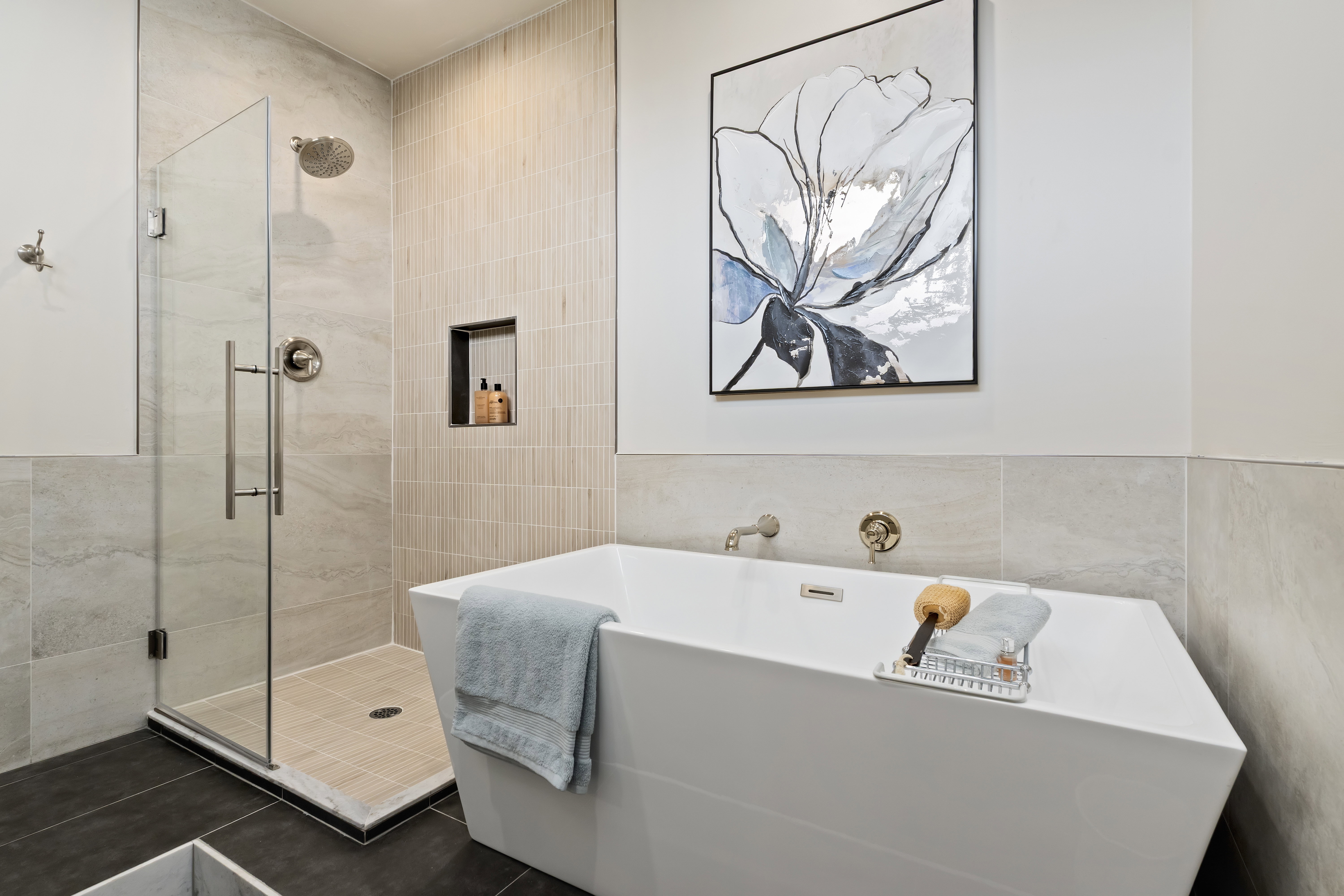 Bathroom with tile walls, a freestanding bath, and a stall shower
