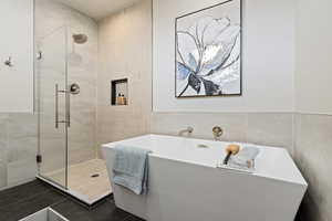 Bathroom with tile walls, a freestanding bath, and a stall shower