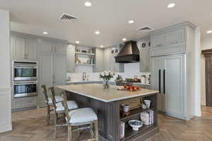 Kitchen featuring open shelves, stainless steel double oven, decorative backsplash, a kitchen bar, and custom range hood