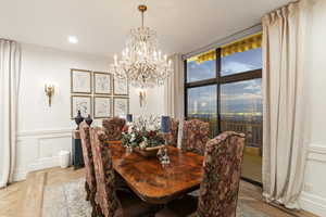 Dining space with a wainscoted wall, a chandelier, a decorative wall, and recessed lighting