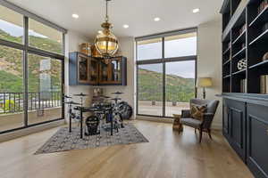 Dining space with a wall of windows, light wood-style flooring, a mountain view, recessed lighting, and a chandelier