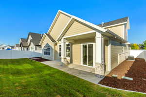 Rear view of house featuring a fenced backyard, a patio area, stone siding, and a residential view