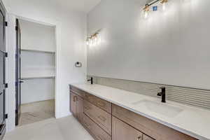 Bathroom featuring double vanity, light tile patterned floors, and a walk in closet