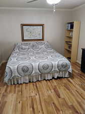 Bedroom featuring wood finished floors and crown molding