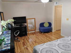 Bedroom with crown molding, light wood-style floors, an office area, and a ceiling fan